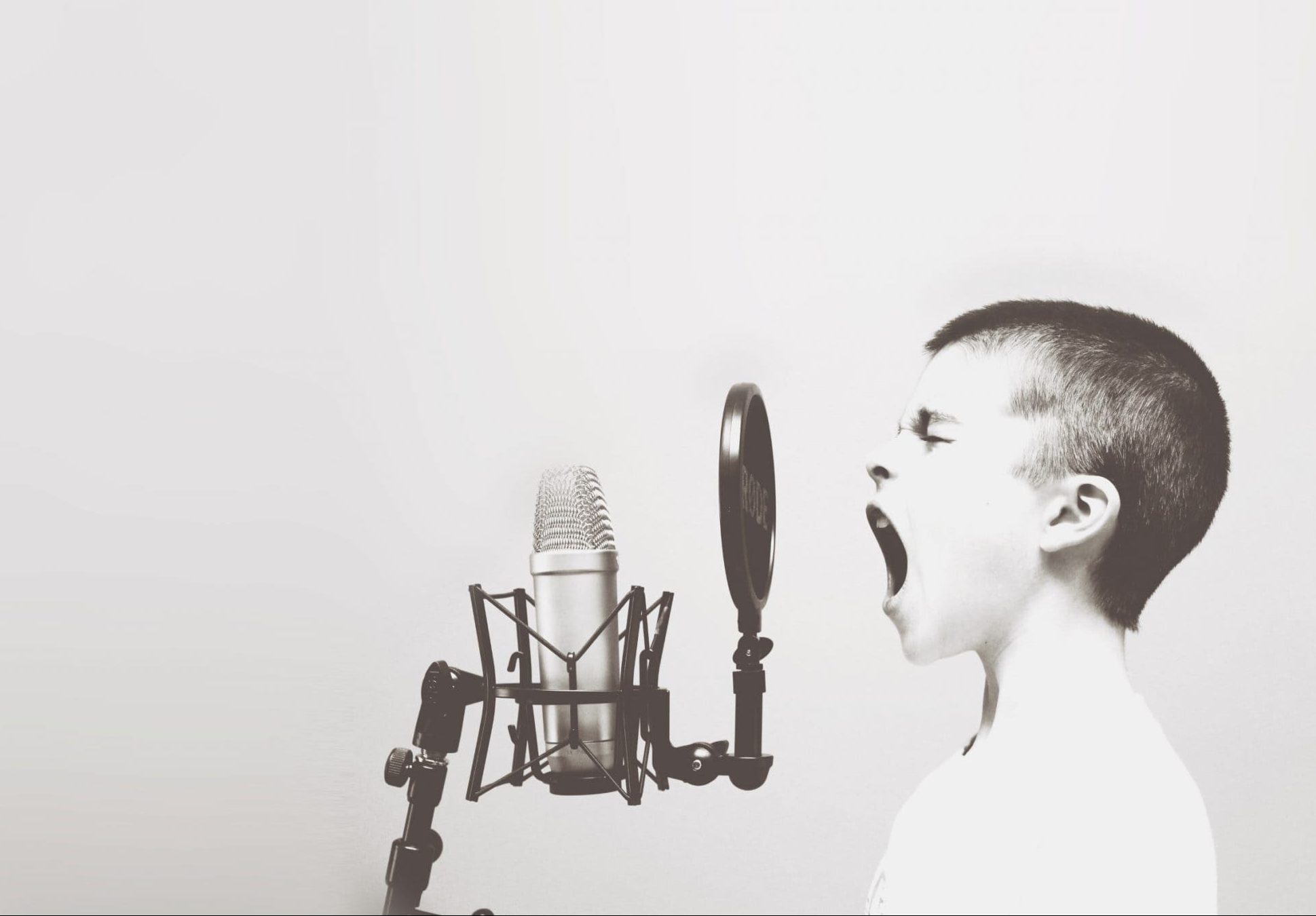 Et barn står og råber eller synger højlydt ind i en mikrofon.